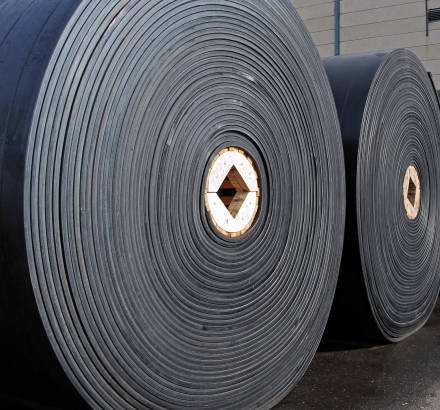 New industrial conveyor belts packed in rolls.